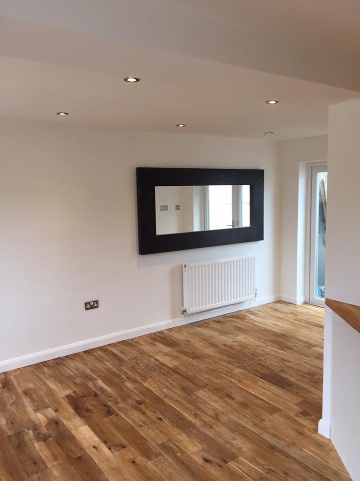 A freshly painted open-plan living room with crisp white walls and oak flooring, decorated by Steve Brady Interiors in East Devon